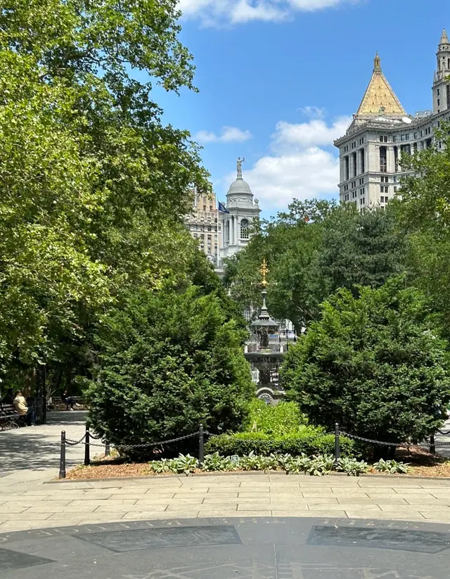 City Hall Park with trees and civic towers in sun, photographed by Kareem Abdo
